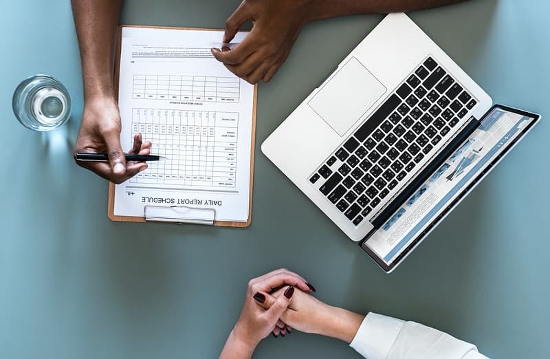 Top view of two people with laptop and paper form